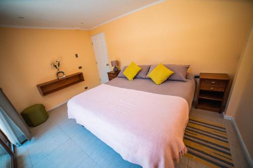 1 dormitorio con 1 cama blanca grande con almohadas amarillas en Cajón del Maipo Lodge, en San José de Maipo