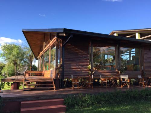 a log cabin with a porch and tables and chairs at Al Kamar Cabañas Lodge in Santa Ana