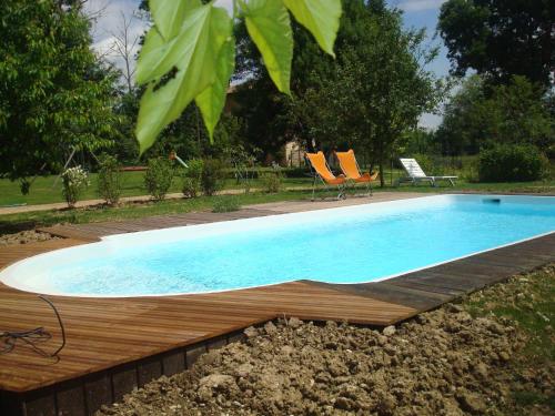 - une piscine avec deux chaises dans la cour dans l'établissement Gîte au Martin Pêcheur, à Laiz