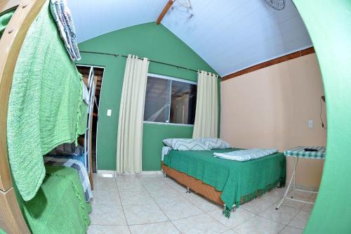 a green room with a bed and a window at Pousada Pontal do Moleque in Carrancas