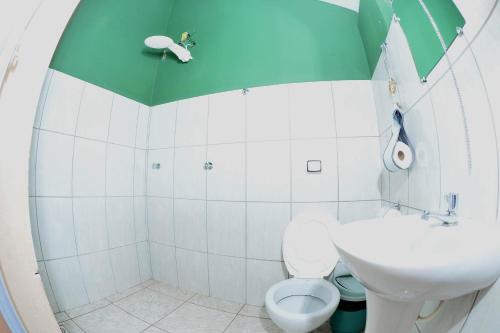uma casa de banho com um WC branco e um tecto verde em Pousada Pontal do Moleque em Carrancas