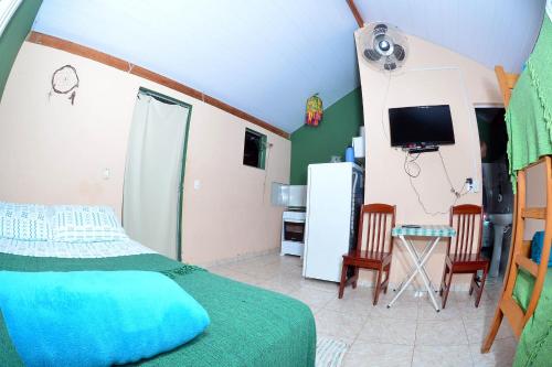 a bedroom with a bed and a tv and a kitchen at Pousada Pontal do Moleque in Carrancas