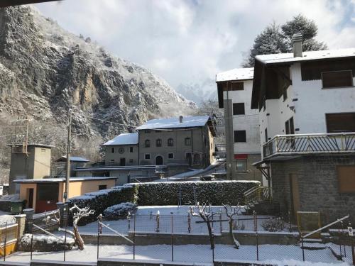 een met sneeuw bedekte stad met gebouwen en een berg bij Il Capriolo in Piazzatorre