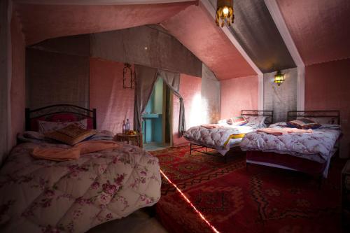 two beds in a room with pink walls at Auberge Sahara Garden in Lac Yasmins