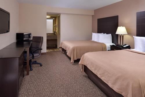 a hotel room with two beds and a desk and a television at Airport Inn in Nederland
