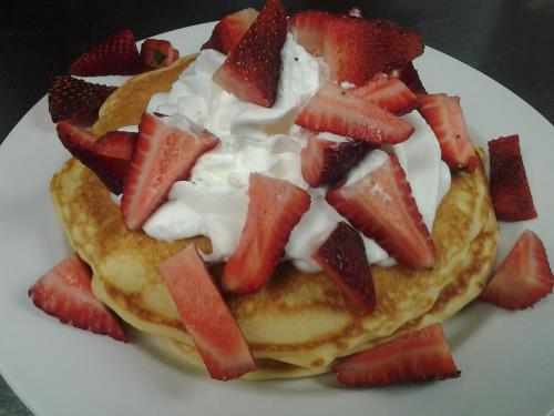 a plate of pancakes with strawberries and whipped cream at Atlantic Breeze Motel & Apartments in Ocean City