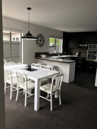 uma cozinha com uma mesa branca e cadeiras brancas em Home By Hagley Park em Christchurch