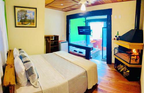 a bedroom with a large bed and a television at Pousada Pináles in Visconde De Maua