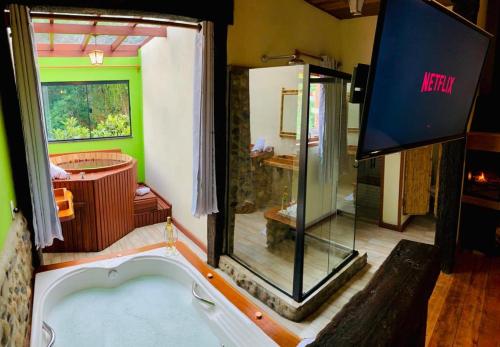 baño con bañera de hidromasaje y espejo en Pousada Pináles, en Visconde De Maua