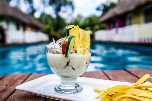 a drink sitting on a plate next to a pool at Las Dunas Surf Resort in Aposentillo