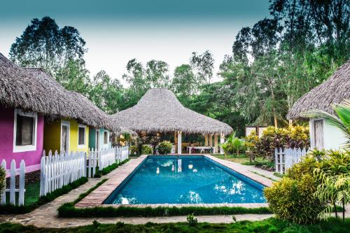 a resort with a swimming pool in front of two huts at Las Dunas Surf Resort in Aposentillo
