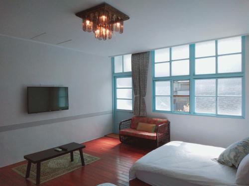 1 dormitorio con 1 cama, TV y silla en 小時公館, en Yuli