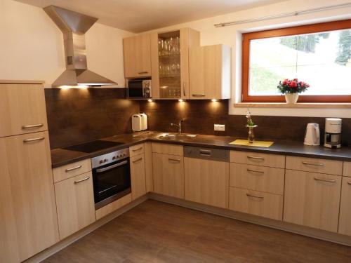 a kitchen with wooden cabinets and a sink and a window at Haus Dabaklamm in Kals am Großglockner