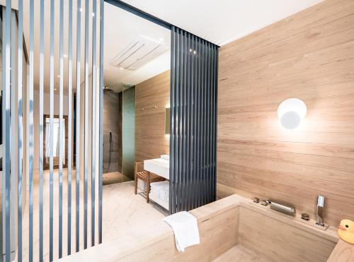 a bathroom with a tub and a shower with wooden walls at Patio 7 in Seoul