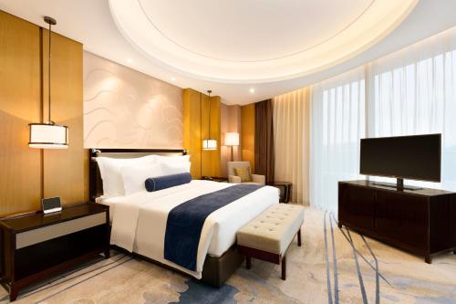 a hotel room with a bed and a television at Wyndham Chongqing Yuelai in Chongqing