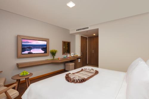 a bedroom with a bed and a tv on the wall at Libra Hotel Nha Trang in Nha Trang