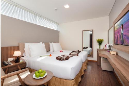 a hotel room with two beds and a table at Libra Hotel Nha Trang in Nha Trang