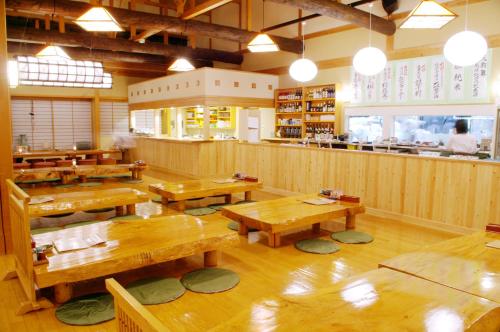 un restaurante con mesas de madera y un bar en Onsen Yupopo en Senboku