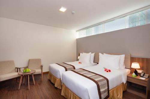 a hotel room with two beds and a window at Libra Hotel Nha Trang in Nha Trang
