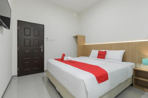 a bedroom with a large bed with a red blanket at RedDoorz near Mall SKA Pekanbaru in Pekanbaru