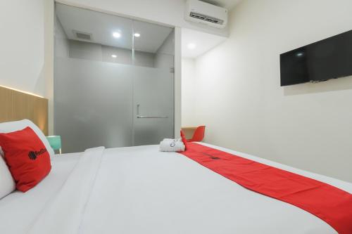 a bedroom with a large white bed with red pillows at RedDoorz near Mall SKA Pekanbaru in Pekanbaru