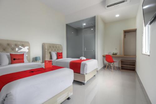 Cette chambre comprend deux lits et un bureau. dans l'établissement RedDoorz near Mall SKA Pekanbaru, à Pekanbaru