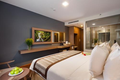 a hotel room with a large bed and a television at Libra Hotel Nha Trang in Nha Trang