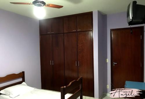 Schlafzimmer mit einem Bett, Holzschränken und einem Deckenventilator in der Unterkunft Casa di Angeli in Barretos