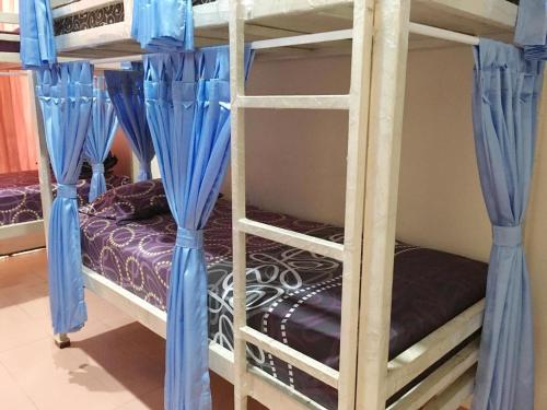 a bedroom with two bunk beds with blue curtains at Cendana Mulia Hostel Bogor in Bogor