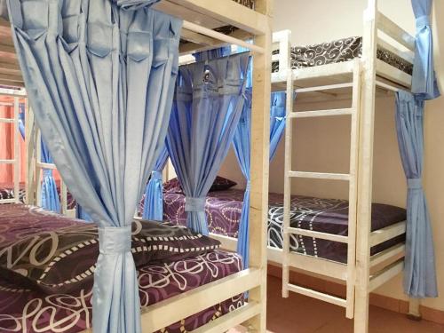 a bedroom with two bunk beds with blue curtains at Cendana Mulia Hostel Bogor in Bogor