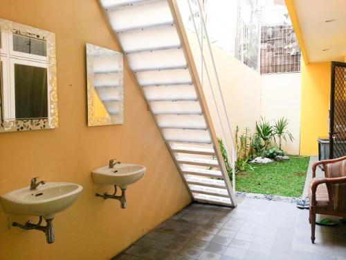 uma casa de banho com 2 lavatórios e uma escada com uma janela em Cendana Mulia Hostel Bogor em Bogor