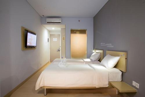 a bedroom with a large white bed and a television at Kyriad Fatmawati Jakarta in Jakarta