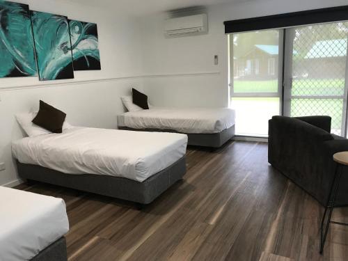 a room with two beds and a couch and a chair at Cobram Barooga Golf Resort in Barooga