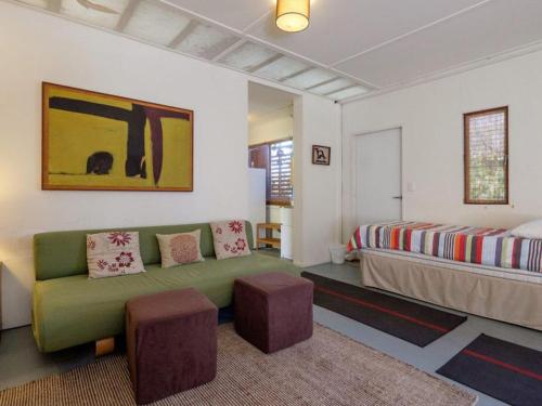 un soggiorno con divano verde e letto di Eddies Place by Discover Stradbroke a Point Lookout