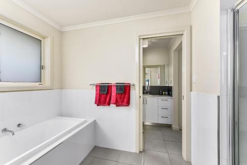 a white bathroom with a tub and a sink at City Fringe Apartment in Mount Gambier