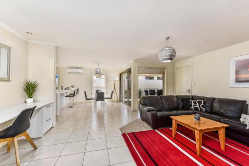 un soggiorno con un divano in pelle nera e un tavolo di City Fringe Apartment a Mount Gambier