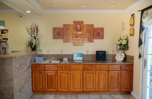 a kitchen with wooden cabinets and paintings on the wall at Sea Breeze Inn - San Simeon in San Simeon