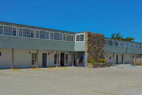 a large building with a stone column in a parking lot at Sea Breeze Inn - San Simeon in San Simeon