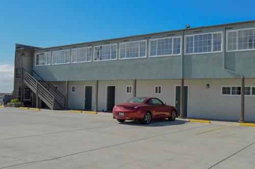 a red car parked in front of a building at Sea Breeze Inn - San Simeon in San Simeon