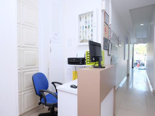 a room with a desk with a computer and blue chairs at TY Hotel in Kuala Terengganu