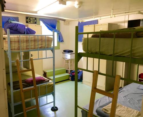 a room with three bunk beds and two chairs at Base Camp Anchorage Hostel in Anchorage