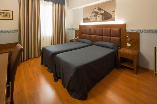 a bedroom with a large bed with a wooden headboard at Hotel Terminus & Plaza in Pisa