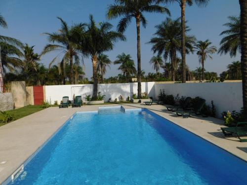 a swimming pool with palm trees in the background at CAP BAY in Cap Skirring