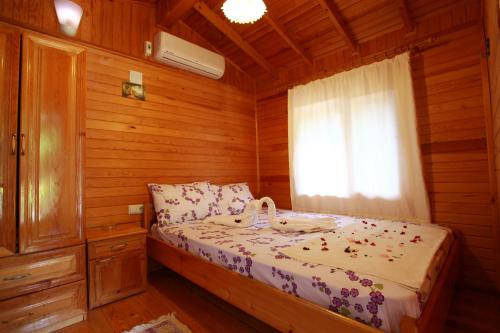 a bedroom with a bed in a wooden cabin at Olympos Doga Pansiyon in Olympos