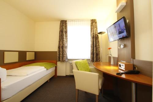 a bedroom with a bed and a desk with a computer at City Hotel Freiburg in Freiburg im Breisgau