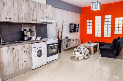 uma cozinha com paredes cor de laranja e uma máquina de lavar roupa em Central Beauty em Lerápetra