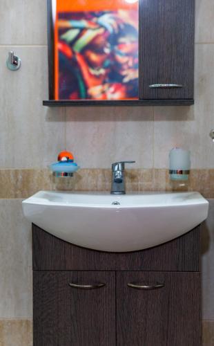 a white sink in a bathroom with a painting at Central Beauty in Ierapetra
