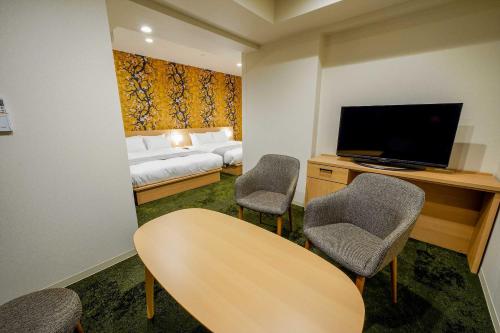 a hotel room with a bed and a television and chairs at RESI STAY Gojozaka in Kyoto