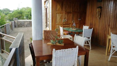a porch with a wooden table and white chairs at Chez Clenya in Rodrigues Island