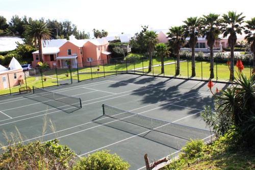 a tennis court with palm trees and houses at The Reefs Resort and Club in Southampton